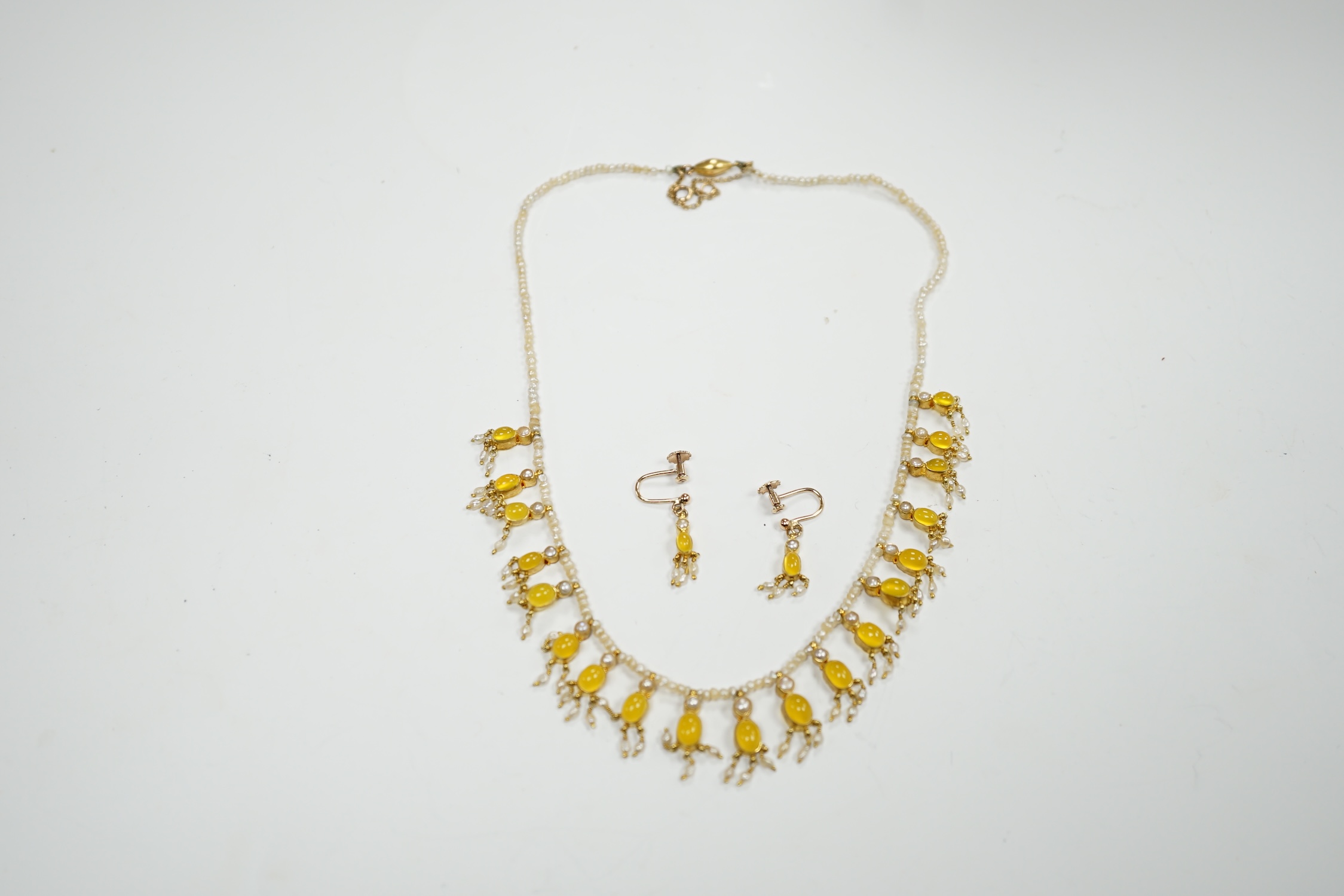 An early 20th century seed pearl and yellow chalcedony set drop necklace with yellow metal clasp, 38cm. and a pair of matching drop ear clips, stamped 375.